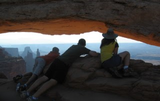 three kids leaning into Mesa Arch