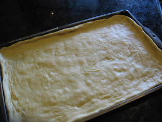 yeast dough spread out on baking sheet