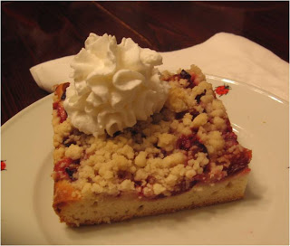 Slice of prune plum cake with dollop of whipped cream