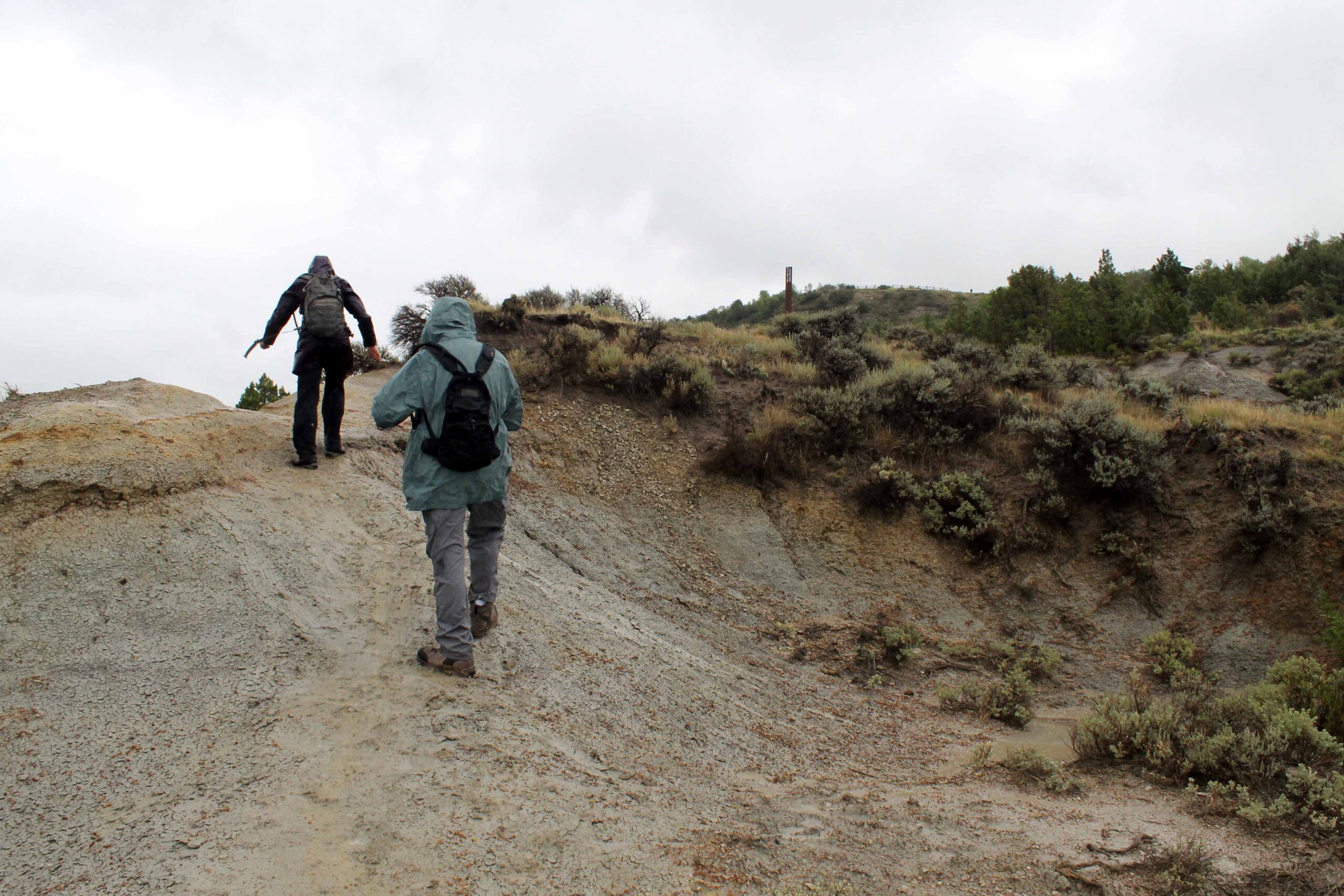 Hikers teetering up a muddy trail in the badlands of Theodore Roosevelt National Park