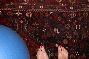 blue exercise ball, bare feet on Oriental rug
