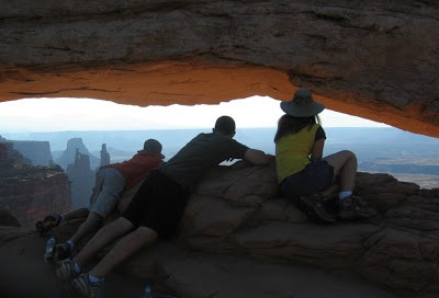 three kids leaning into Mesa Arch